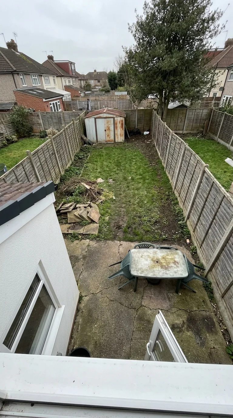 Neglected back garden with a cracked patio, seen from an upstairs window