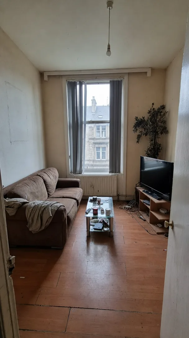 Tired living room with a sagging sofa and bare bulb